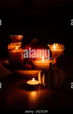Autumn thanksgiving home decor with pumpkins and burning candles on table. Dark moody banner decorations with pumpkin and candles Stock Photo