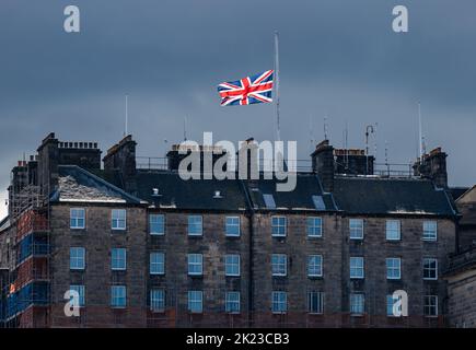 Union Jack flag flying at half mast after death of HM Queen Elizabeth II on Edinburgh city centre tenement rooftop, Scotland, UK Stock Photo
