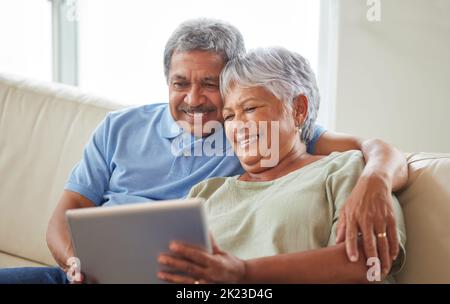 Senior couple, tablet and communication on social media or video call with elderly husband and wife relaxing on the couch at home. Man and woman Stock Photo