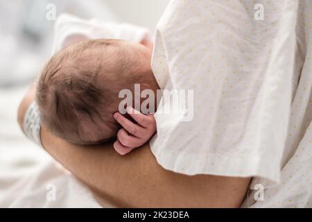A newborn baby in his mother's arms in the hospital bed Stock Photo
