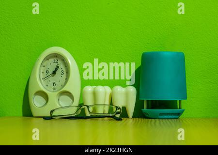 Table watch, sunglasses, pen holder, and two big teeth are on a dentist's table. The dental clinic or office and dental treatment for restoring teeth. Stock Photo