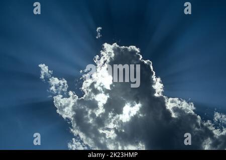 Crepuscular rays burst from behind a cloud Stock Photo