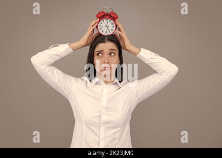 Portrait of young attractive shocked amazed surprised girl hold clock isolated on gray color background. Stock Photo