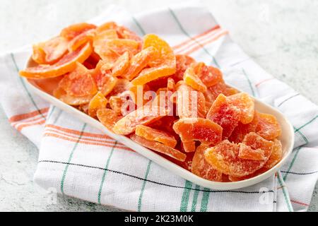 Dried papaya slice on gray background. Dried fruit in sunlight. close up Stock Photo