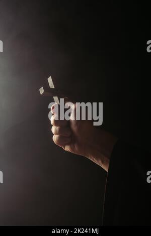 partial view of priest holding holy crucifix on black background,stock image Stock Photo