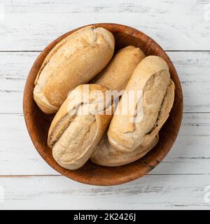 Whole grain french bread, salt bread or pistolet in a bowl over wooden table. Stock Photo