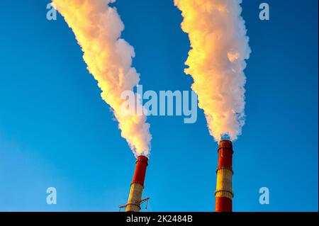 white smoke is coming out of the pipes in the blue sky. High quality photo Stock Photo