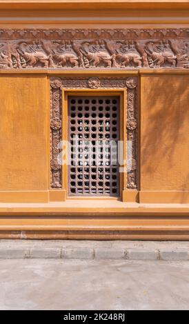 Wooden grid window installed in ornamental wall outside of old stone building Stock Photo