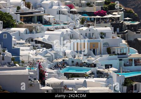 Oia, Santorini, Greece - July 3, 2021: Whitewashed houses with terraces and pools and a beautiful view in Oia on Santorini island, Greece Stock Photo