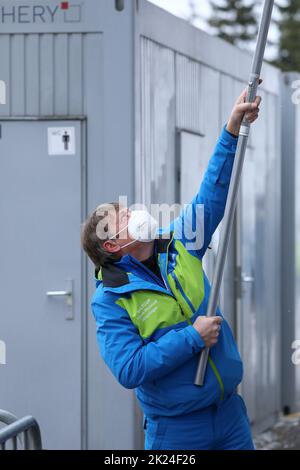Manchmal legt der Chef selbst Hand an: Generalsekretär Joachim Häfker entfernt Eis aus der Dachrinne am Funktionsgebäude beim FIS Weltcup Skispringen Stock Photo