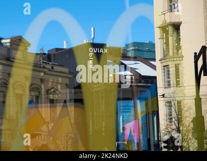 Helsinki, Finland - February 26, 2022: Yellow McDonald’s Golden Arches logo reflecting from the window with a rally against Russia’s military actions Stock Photo