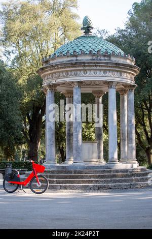 Rome, Italy - October 10, 2020: Neoclassical small circular Temple of Diana (Tempietto di Diana) in Villa Borghese gardens, red bicycle red bicycle st Stock Photo