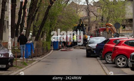 Workers carry out repair work on the city sewer. Tractor, repair in the city, hole in the asphalt. Stock Photo