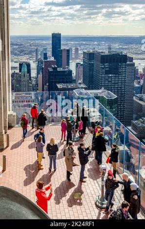 People tourists on the observation deck of Rockefeller Center, view from high angle, New York City with lots of skyscrapers and Hudson river in the ba Stock Photo