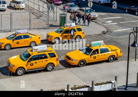Different car models of Yellow taxi cabs parked in side street in Chelsea, New York City during sunny winter day, horizontal Stock Photo