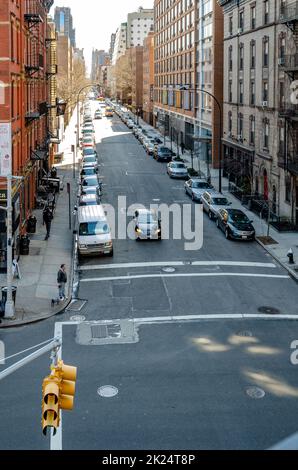 City street with parked cars and traffic in Chelsea aerial view from the High Line Rooftop Park, New York City during sunny winter day, vertical Stock Photo