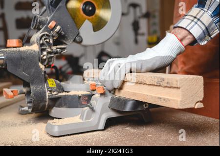 Carpenter using an electric circular saw, cutting piece of wood. High quality photo. Stock Photo