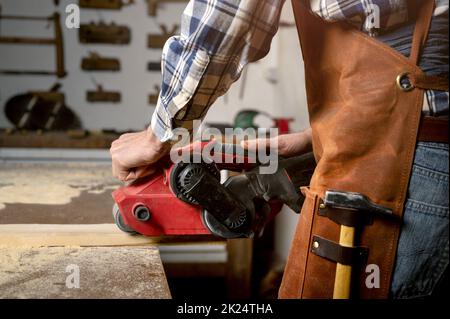 Carpenter sanding wood with belt sander at workshop in wooden board project or woodworking carpentry. High quality 4k footage Stock Photo
