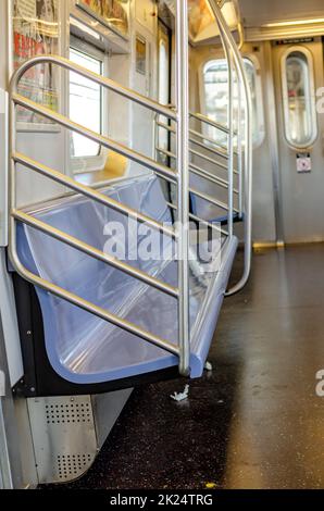 Empty blue Benches in Subway New York City, view from the side, driving above ground, sunny winter day, vertical Stock Photo