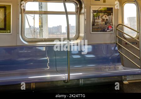 Empty blue Benches in Subway close-up, view from the front, New York City, driving above ground, sunny winter day, horizontal Stock Photo