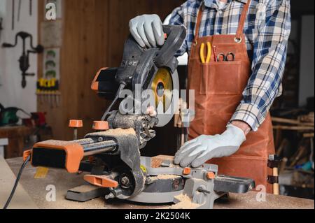 Carpenter using an electric circular saw, cutting piece of wood. High quality photo. Stock Photo