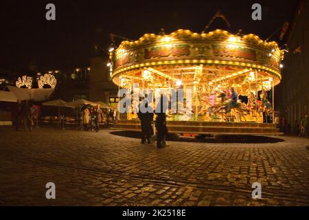 London, United Kingdom - November 25th, 2006: People walking around and watching carousel illuminated in evening at Covent Garden which is popular tou Stock Photo