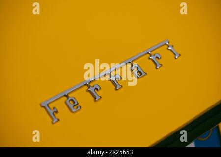 Como, Italy - May 22, 2022: Illustrative editorial image of an Ferrari logo on a vintage yellow car hood. Stock Photo