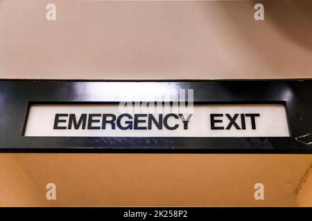 An emergency exit sign above a door in a community centre Stock Photo