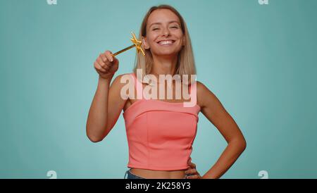 Magician wizard woman gesturing with magic wand fairy stick, making wish come true, casting magician spell, advertising holidays sale discount. Young witch girl isolated on blue studio background Stock Photo