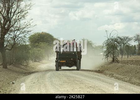 Ngorongoro Conservation Area, Tanzania - 7 Novembre 2017: African men over a truck in a dusty road in the tanzanian countryside. Stock Photo