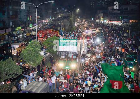 Women's football team members celebrate on their way to the Bangladesh Football Federation House. Bangladesh national women's football team holds the SAFF Women's Championship trophy in an open-top bus on their way to the BFF House from the Hazrat Shahjalal International Airport as thousands of ordinary people greet the players from the roadside. Stock Photo