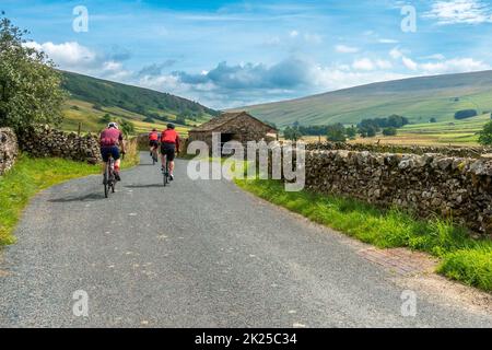 Three male cyclists socialising on bikes on a country lane near Halton Gill with views of Littondale, Yorkshire Dales National Park, North Yorkshire, Stock Photo