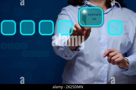 a woman in a striped shirt presses the holographic button with the inscription contact us. Customer support concept Stock Photo