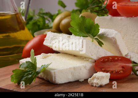 Feta cheese, olives and cherry tomatoes, green herbs and olive oil. Greek snack Stock Photo