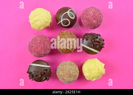Chocolate pralines top view stock images. Chocolate candies on a pink background. Chocolate frame top view. Square-shaped chocolate pralines background Stock Photo