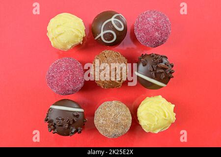 Chocolate pralines top view stock images. Chocolate candies on a red background. Chocolate frame top view. Square-shaped chocolate pralines background Stock Photo