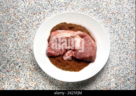 A piece of spiced meat in a plate before frying Stock Photo