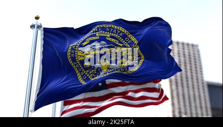 the flag of the US state of Nebraska waving in the wind with the American flag blurred in the background Stock Photo