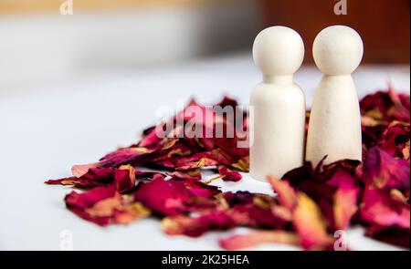 Real love, lover, couple concept. Two wooden figures with red rose petals on white background, standing together isolated on white background. copy space Stock Photo