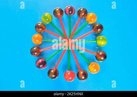 Various colorful lollipops on pastel background. Bright juicy colored lollipops on a light blue background. Lollipops in the form of a flower. Fruit candy Stock Photo