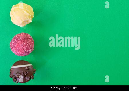 Chocolate bonbons or pralines on green background. Assortment of chocolate pralines on green background with copy space. Flat lay, top view Stock Photo
