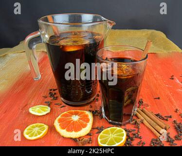 Christmas or New Year hot winter drink, spicy grog cocktail, sangria or mulled wine with tea, lemon, rum, cinnamon, anise. Rustic style. Christmas mulled red wine in a glass on a rustic wooden table Stock Photo