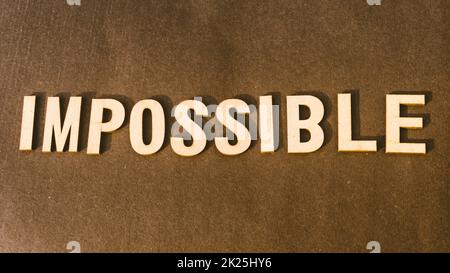 The word Impossible written with Brown Wooden Alphabet stamp on Vintage background. Stock Photo