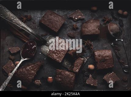 pieces of baked chocolate brownie pie in a metal baking sheet on a black table Stock Photo