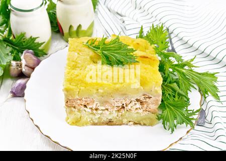 Casserole with potatoes and fish in plate on board Stock Photo