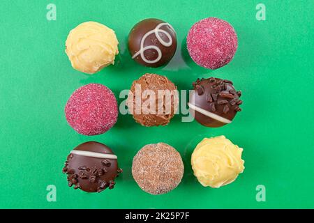 Chocolate pralines top view stock images. Chocolate candies on a green background. Chocolate frame top view. Square-shaped chocolate pralines background Stock Photo