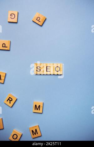 Wooden letters SEO are printed on a light blue background with many different wooden letters in the background. Stock Photo