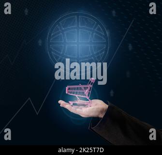 a man's hand holds a miniature shopping cart on a dark blue background, the concept of the start of world sales, the growth of purchases. Online shopping Stock Photo