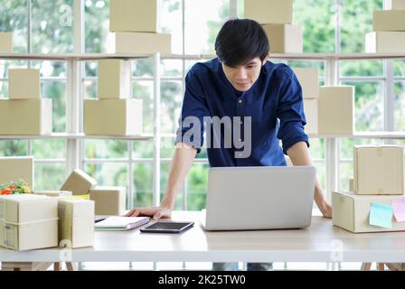Young entrepreneur checking products stock at home office. Work from home concept. Stock Photo