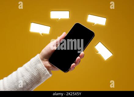 female hand holding smartphone with blank black screen on yellow background Stock Photo